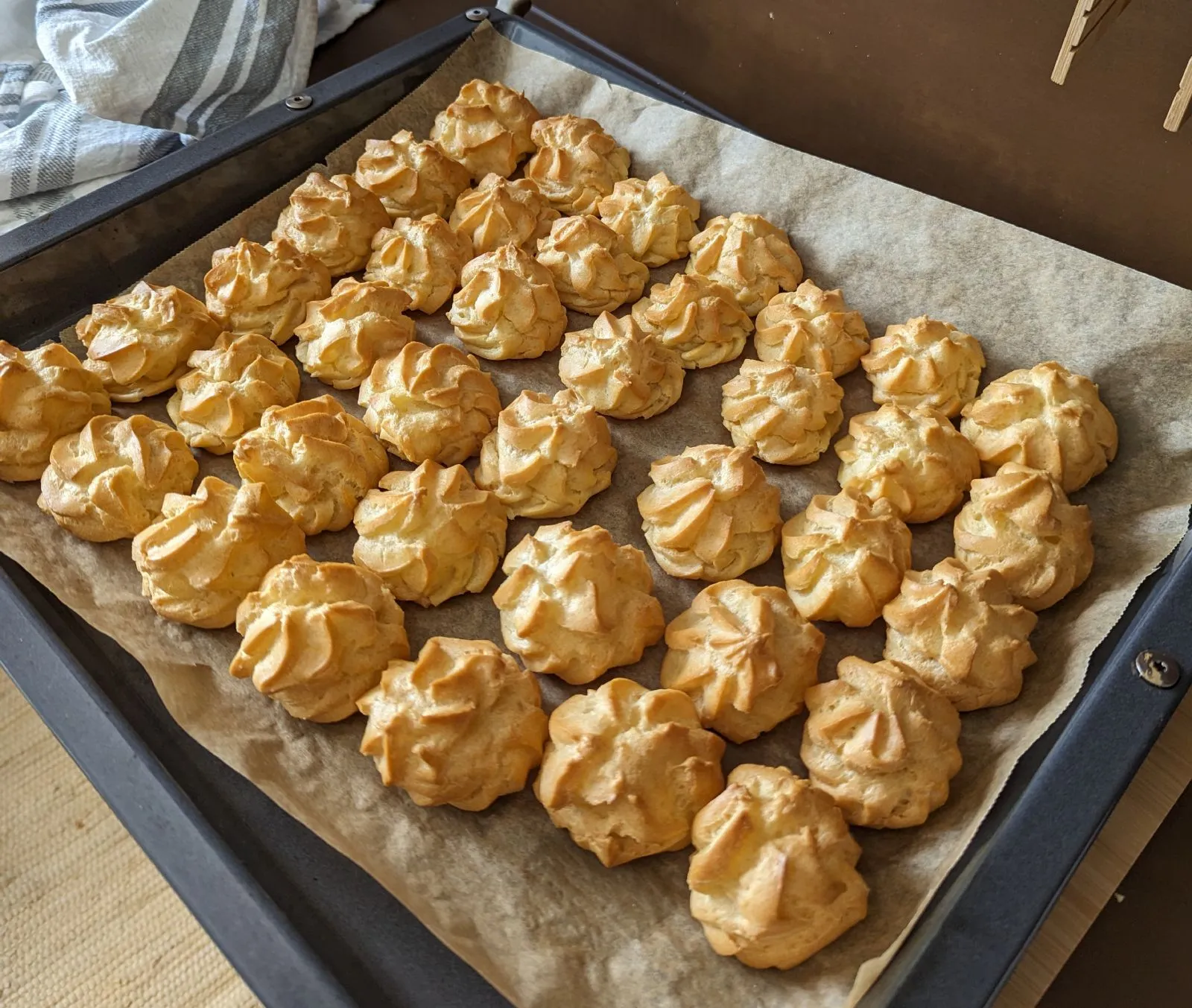Ungefüllte Brandteigkrapferl nach dem Backen auf einem Blech.