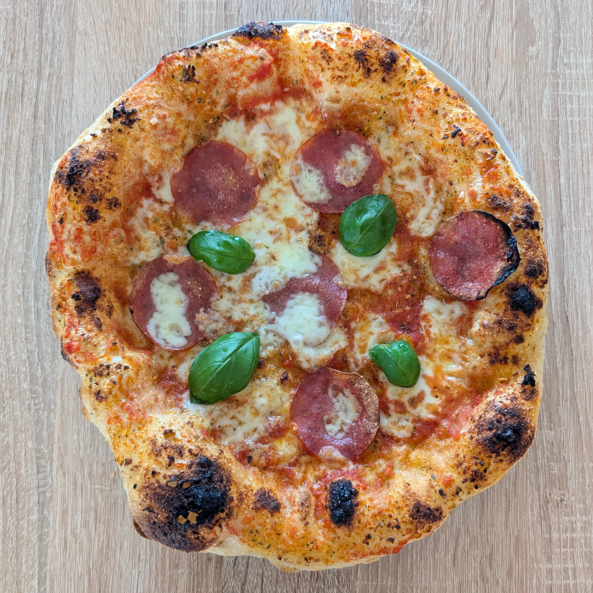Frisch gebackene Pizzen mit aufgegangenem Rand auf einem Teller.