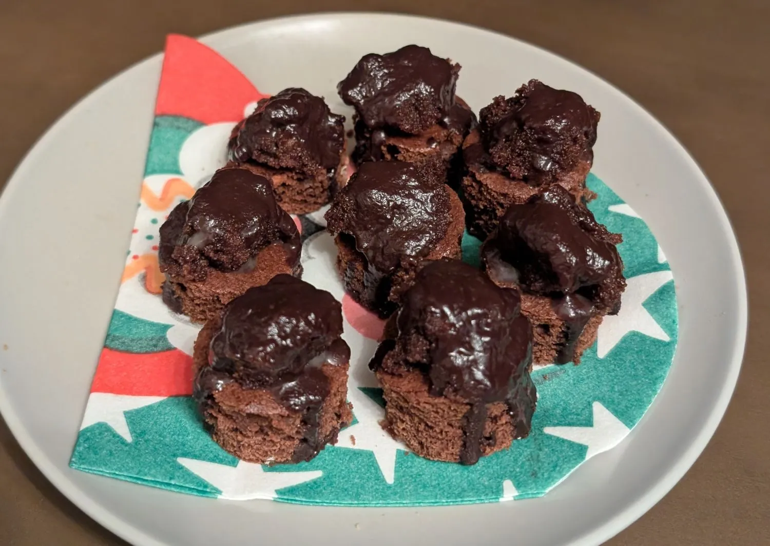 Kleine Punschkrapferl mit Schokoglasur dicht aneinander auf einem Blech.