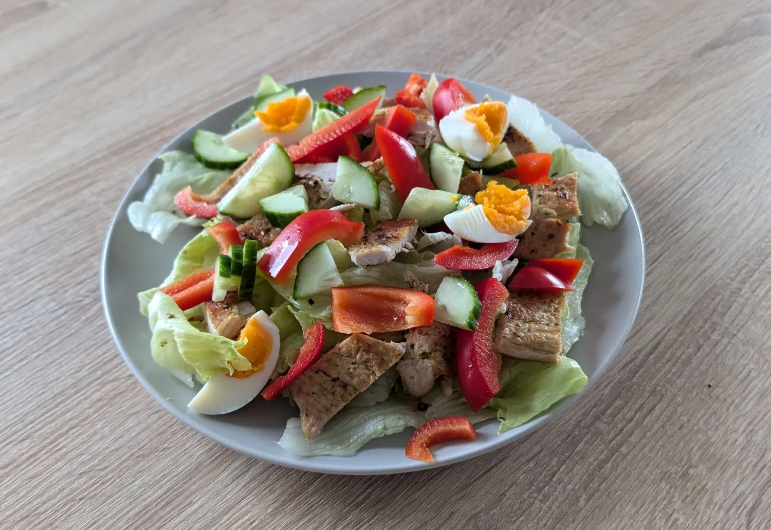 Großer Salatteller mit Putenstreifen, Gurke und Paprika.