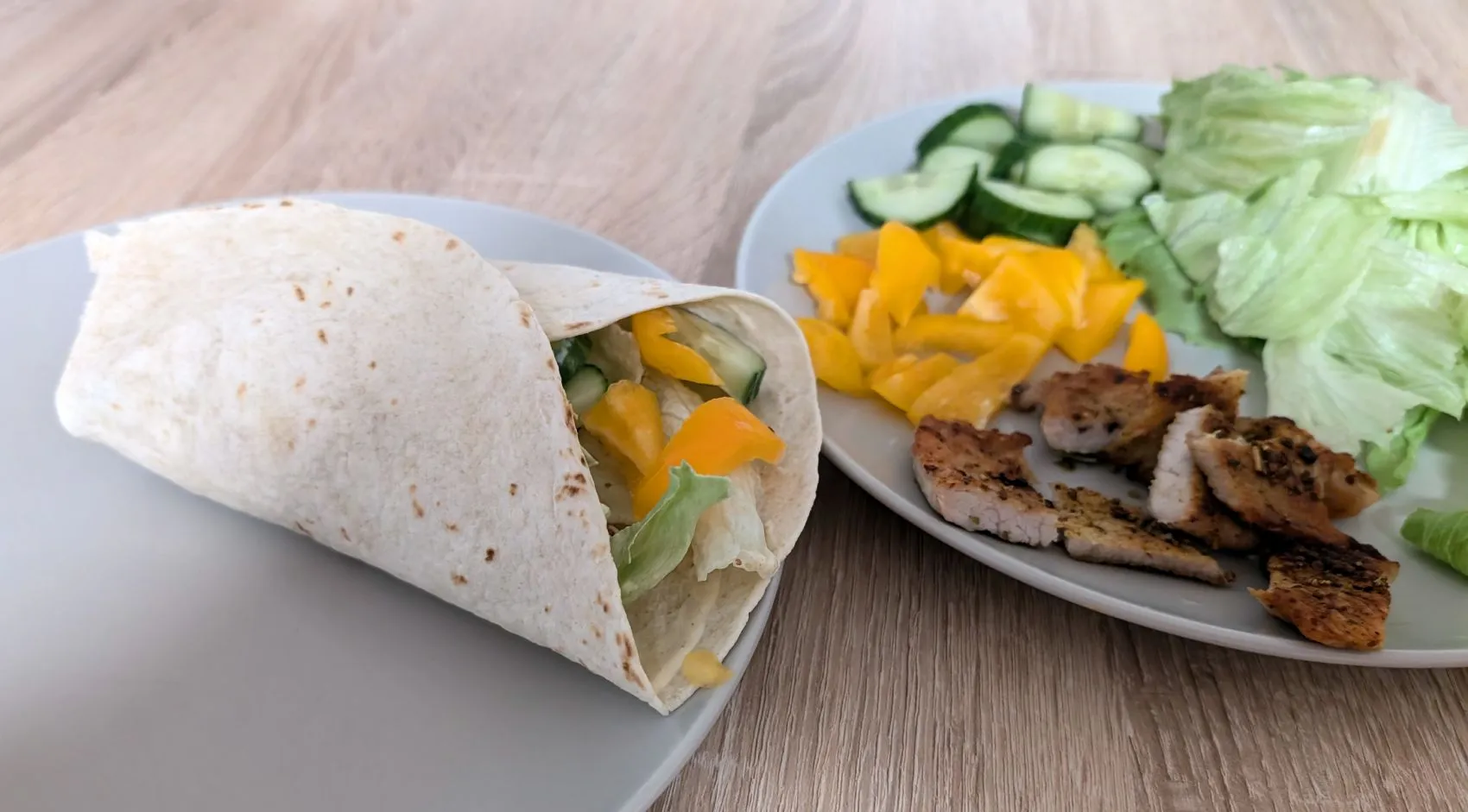 Aufgeschnittener Wrap mit würziger Füllung, Salat, Gurke und Paprika.